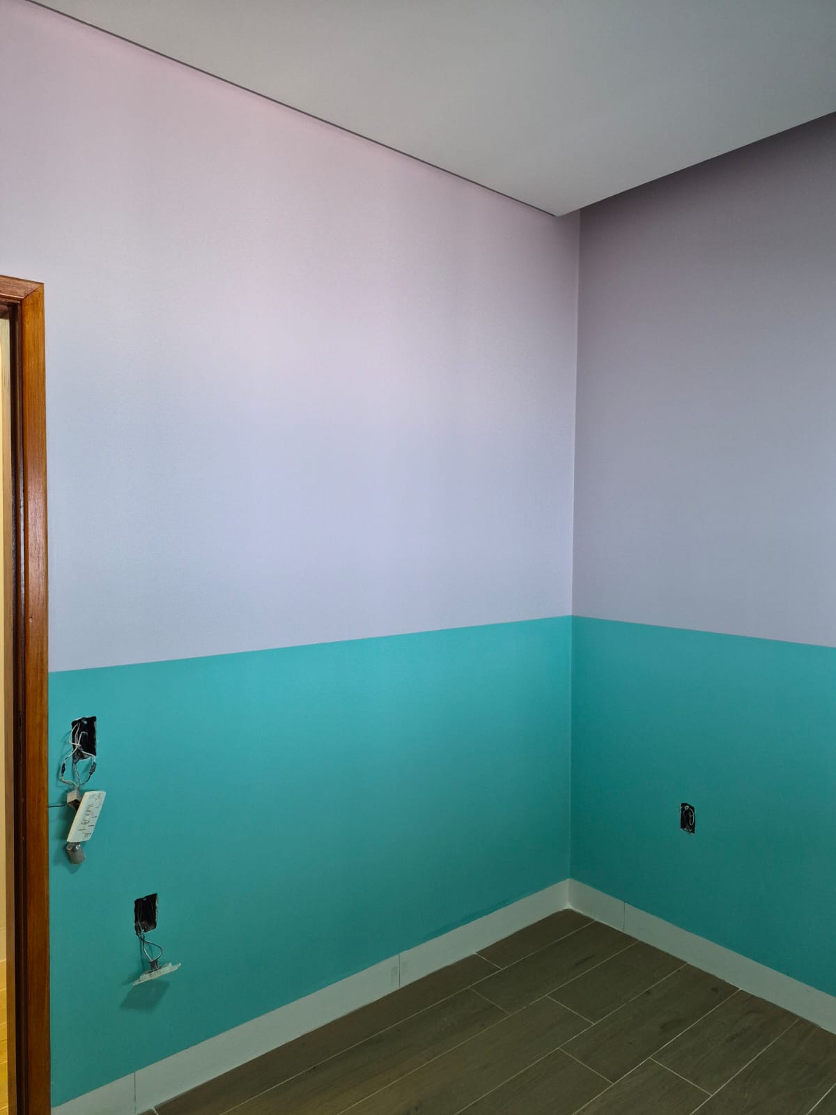 Quarto pintado com parede lilás na parte superior e verde água na inferior