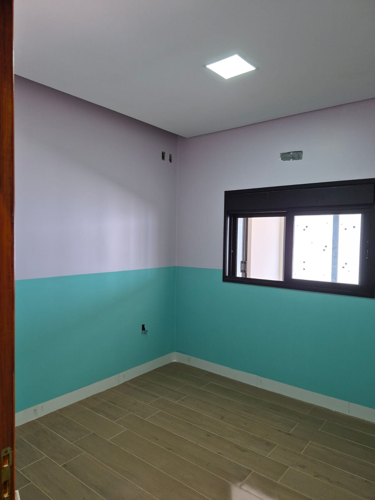 Quarto com janela preta e pintura bicolor lilás e verde água